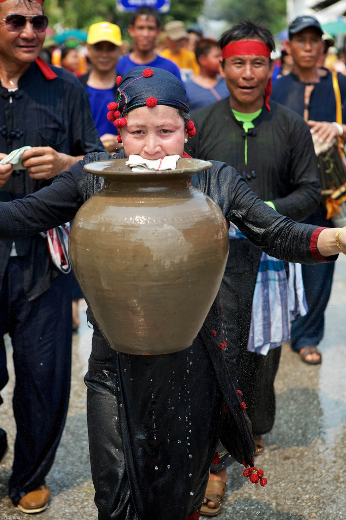 Ethnic minority woman holding a ceramic jar with her teeth at the Lao New Year or Phi Mai Lao parade in Luang Prabang Laos