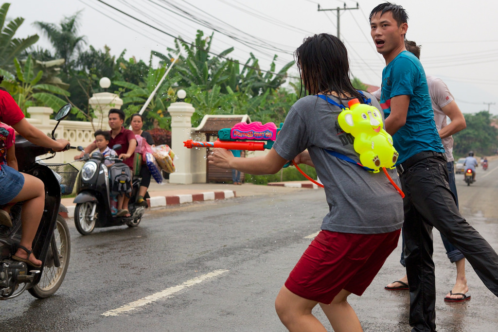 Girl shoots water at motorbike riders in Luang Prabang for Lao New Year